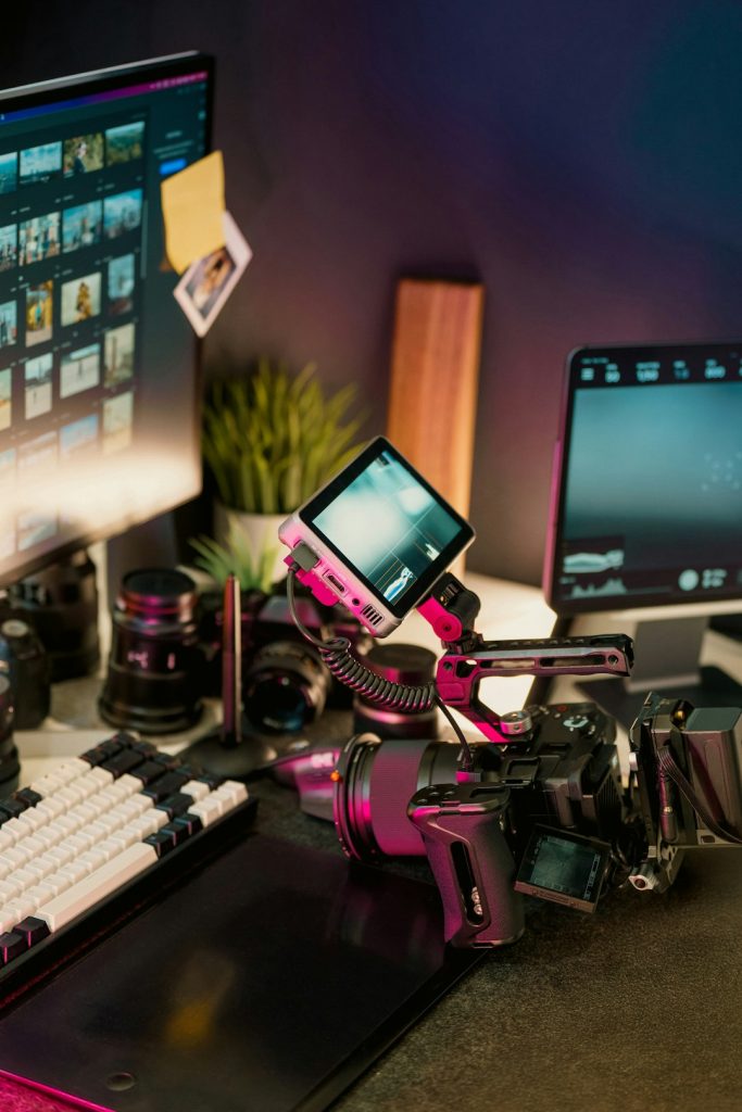 Professional video camera editing setup studio workspace with camera gear, computer screens displaying footage thumbnails, and digital production tools. Perfect environment for content creators and filmmakers