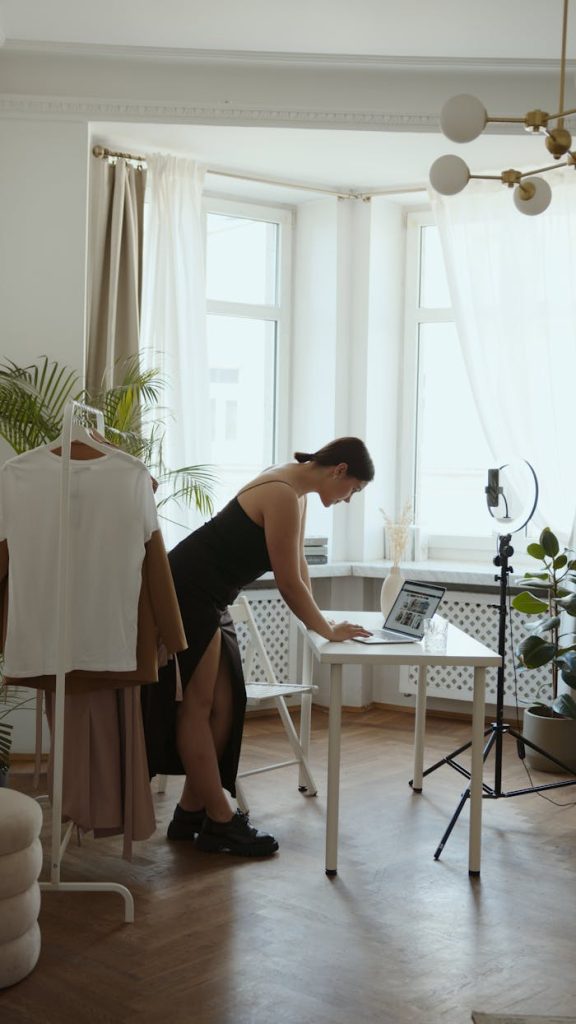 Side view of woman online blogging at home, using a laptop with a ring light.